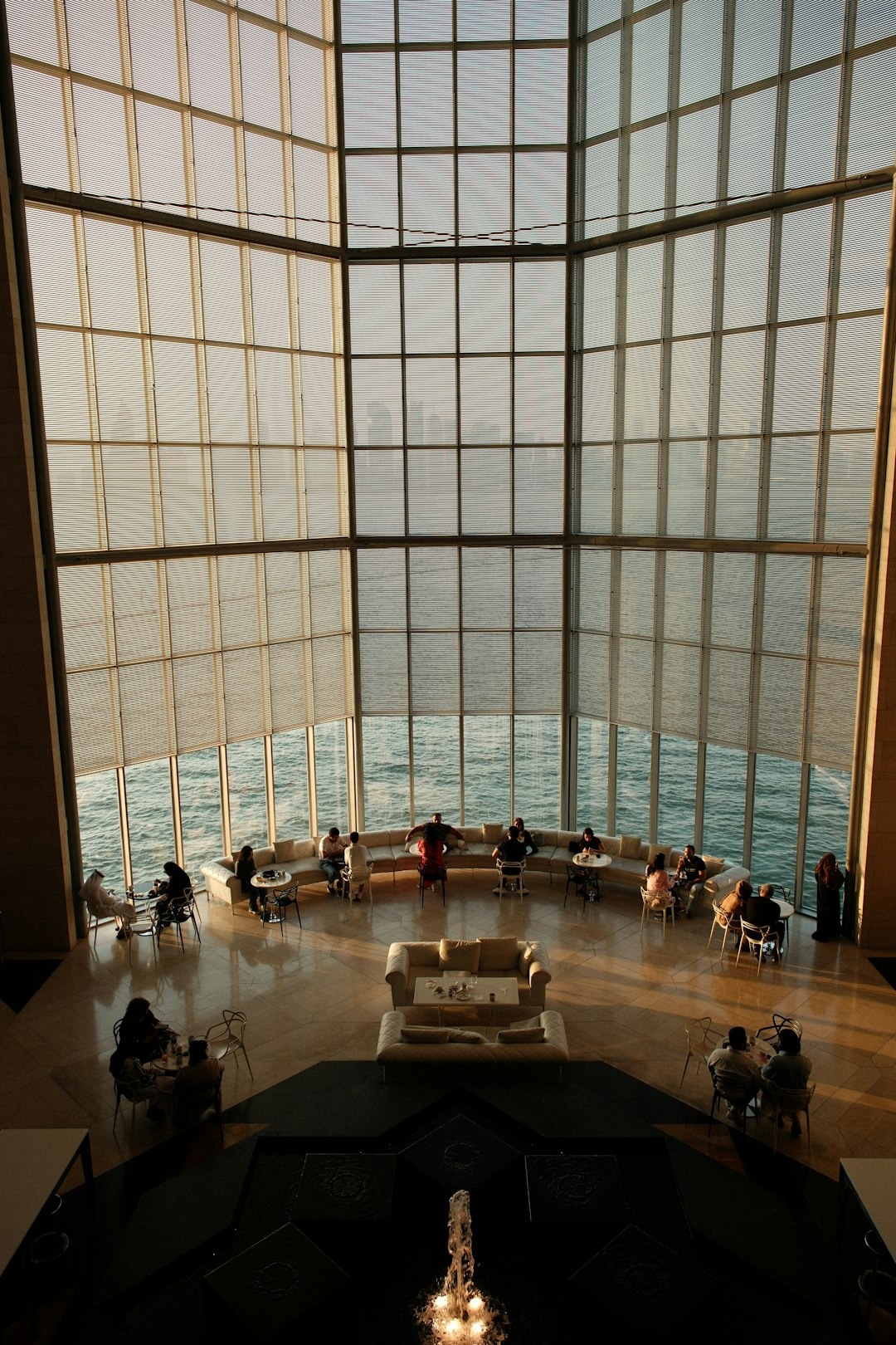 People relaxing in a luxurious lounge overlooking the ocean at sunset.